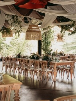 Mesas de madera y sillas crossback decoradas con telas y flores para una recepción