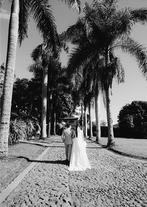 Novios caminando por el sendero de palmas de Hacienda La Tranquera