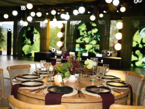 Mesa redonda con vajilla negra y luces colgantes en El Salón